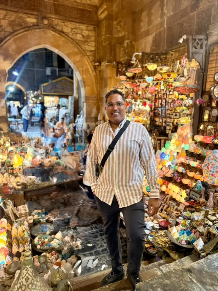 Traveler on stone steps before a wall of colorful lanterns in Khan El Khalili