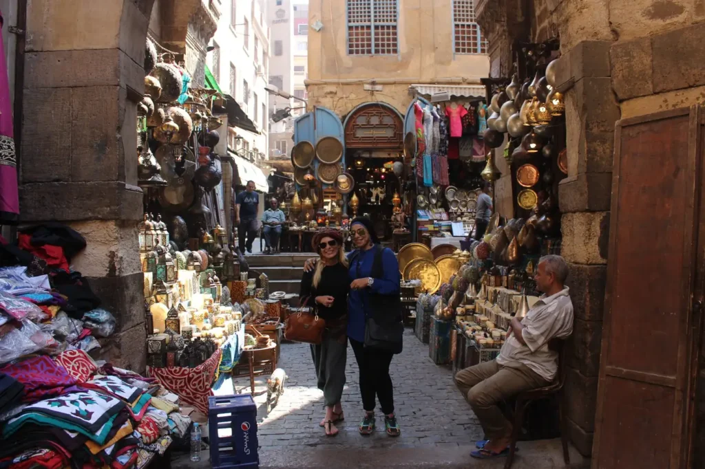 Two travelers posing in a lantern-lined alley of Khan El Khalili bazaar