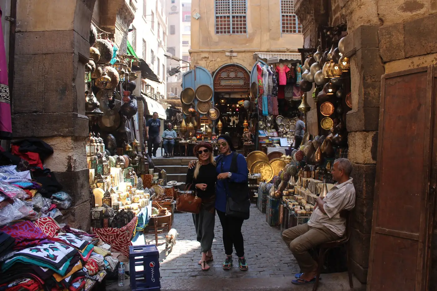 Two travelers posing in a lantern-lined alley of Khan El Khalili bazaar
