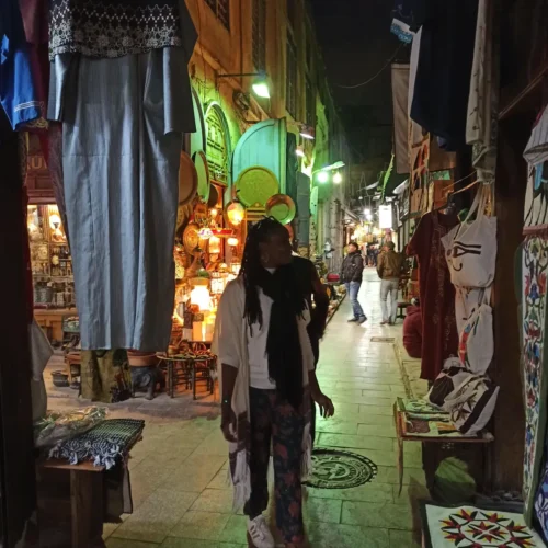 Traveler walking a narrow evening alley lined with brassware in Khan El Khalili