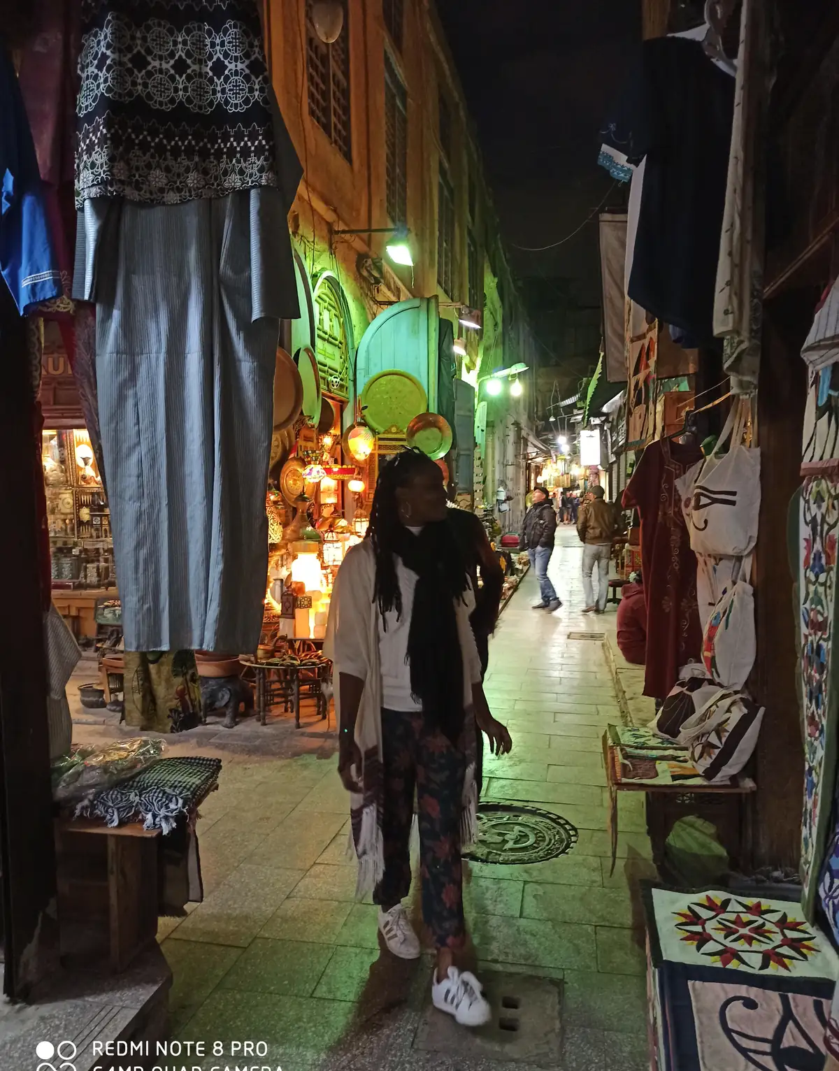 Traveler walking a narrow evening alley lined with brassware in Khan El Khalili