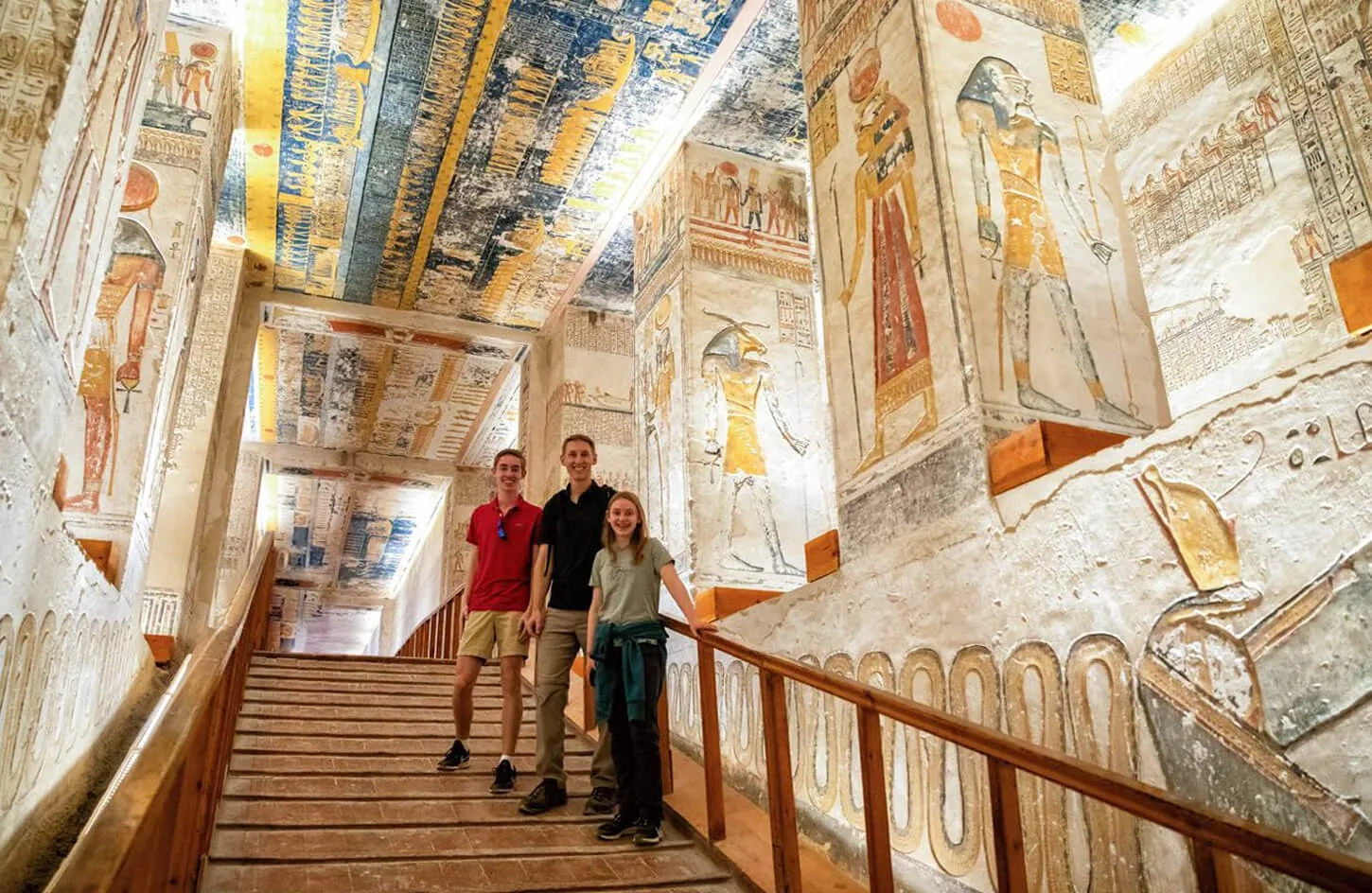 travelers walking through a vibrant painted corridor inside an ancient tomb in valley of the kings luxor