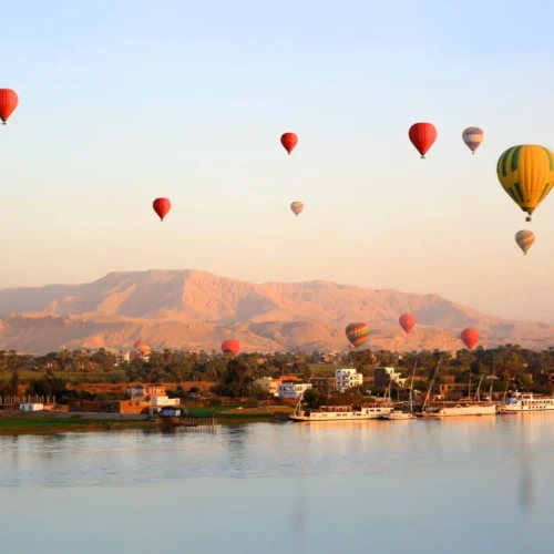 colorful hot air balloon soaring over the nile river and ancient west bank temples in luxor at sunrise