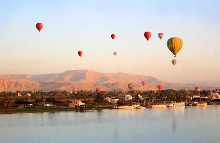 colorful hot air balloon soaring over the nile river and ancient west bank temples in luxor at sunrise