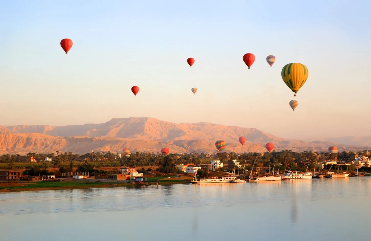 colorful hot air balloon soaring over the nile river and ancient west bank temples in luxor at sunrise