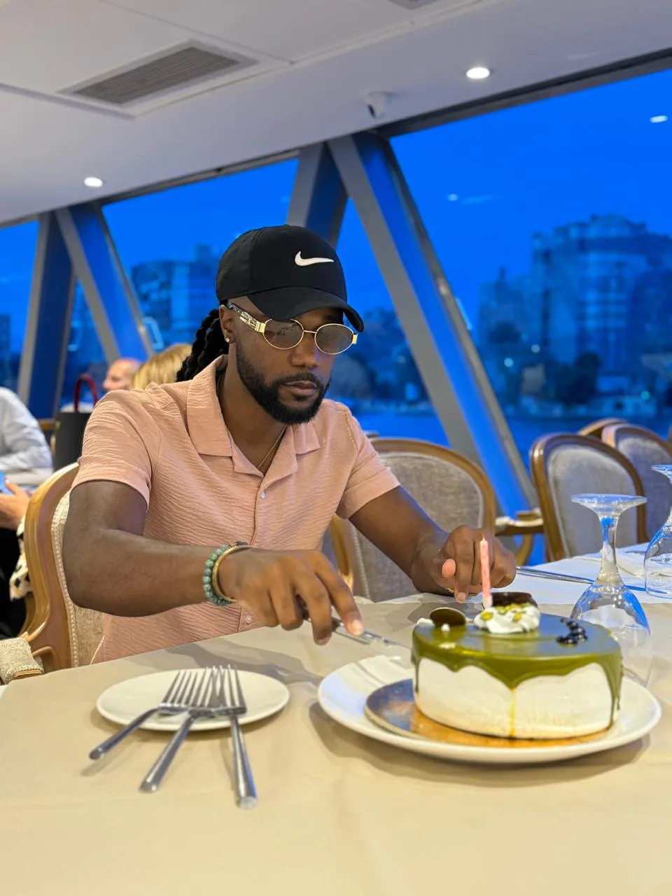 Traveler cutting a cake at a dinner table aboard a Nile cruise at twilight