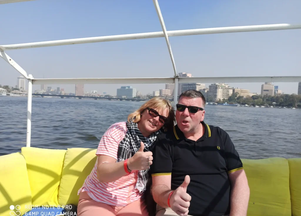 Couple giving thumbs-up on yellow cushions during a Nile boat ride in Cairo
