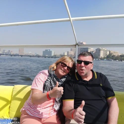 Couple giving thumbs-up on yellow cushions during a Nile boat ride in Cairo