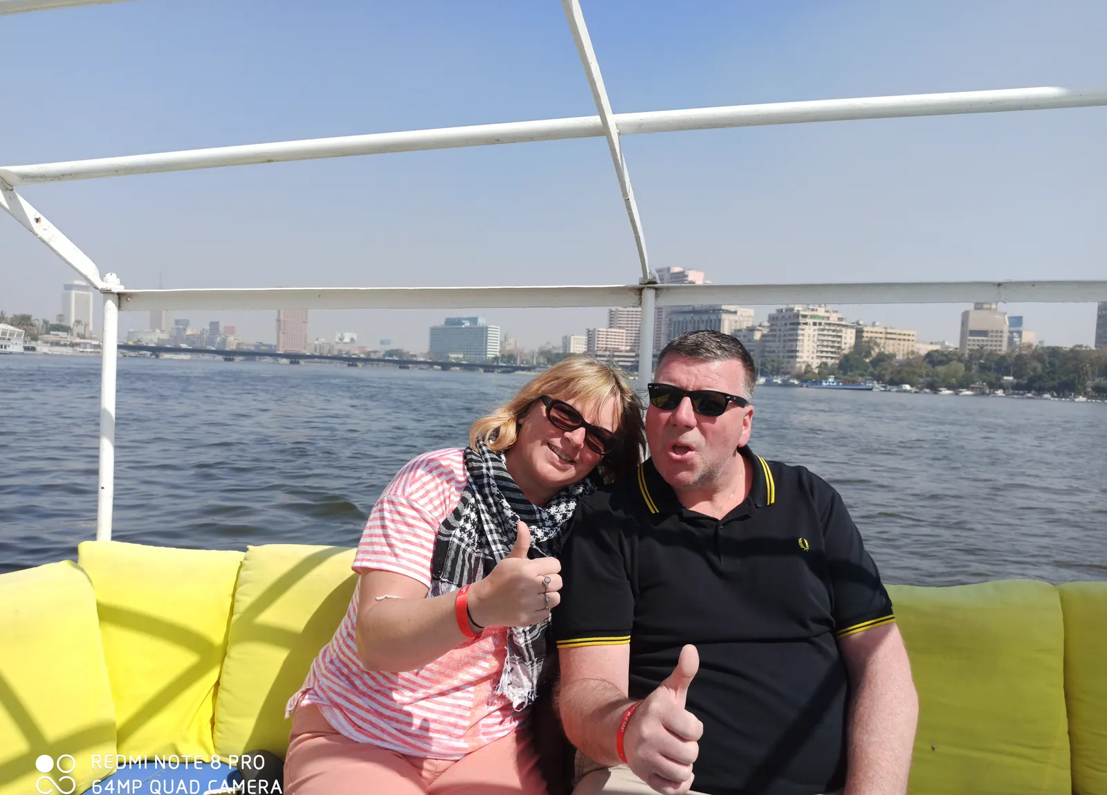 Couple giving thumbs-up on yellow cushions during a Nile boat ride in Cairo