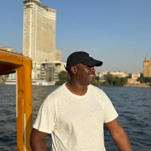 Traveler smiling on a Nile boat with the Grand Nile Tower across the river