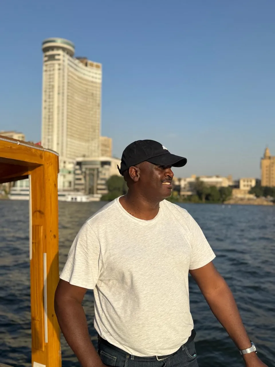 Traveler smiling on a Nile boat with the Grand Nile Tower across the river