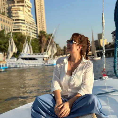 Traveler seated cross-legged on a Nile boat deck with Cairo high-rises behind