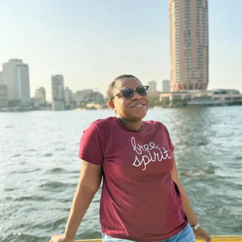 Traveler leaning on a yellow boat railing with the Nile and Cairo skyline behind