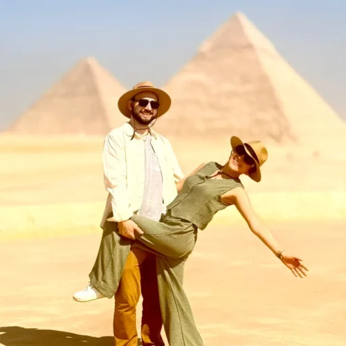 Couple posing playfully with the three Giza pyramids behind