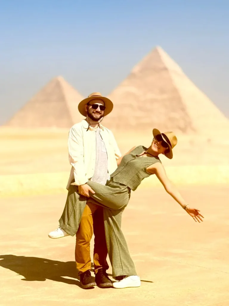 Couple posing playfully with the three Giza pyramids behind