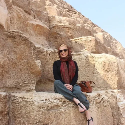 Traveler in a red scarf seated on the blocks of a Giza pyramid