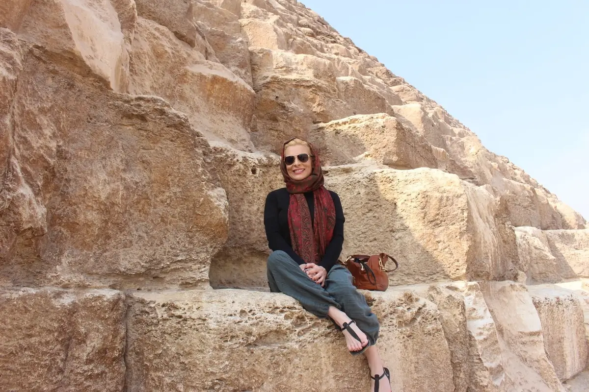 Traveler in a red scarf seated on the blocks of a Giza pyramid
