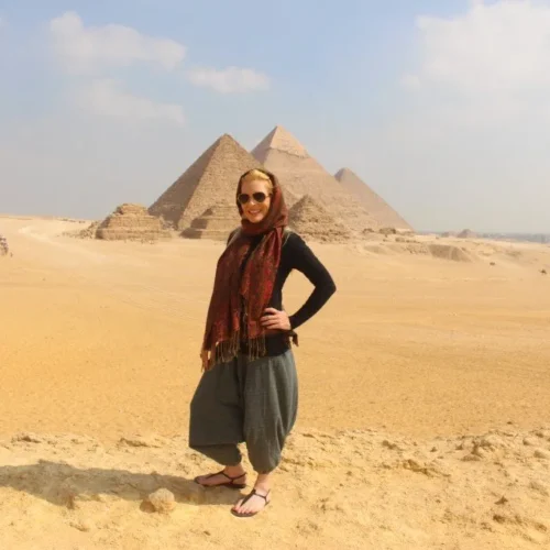 Traveler in a red scarf in front of the three Giza pyramids