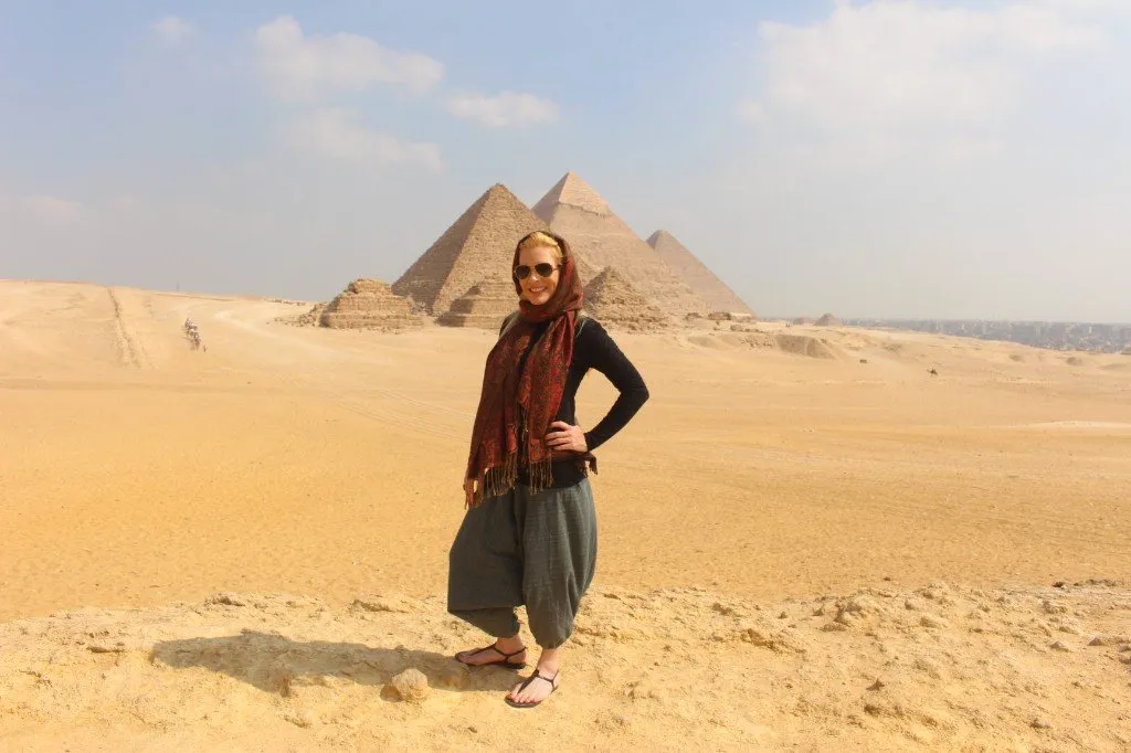 Traveler in a red scarf in front of the three Giza pyramids