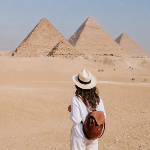 Traveler with a backpack facing the panorama of the Giza pyramids