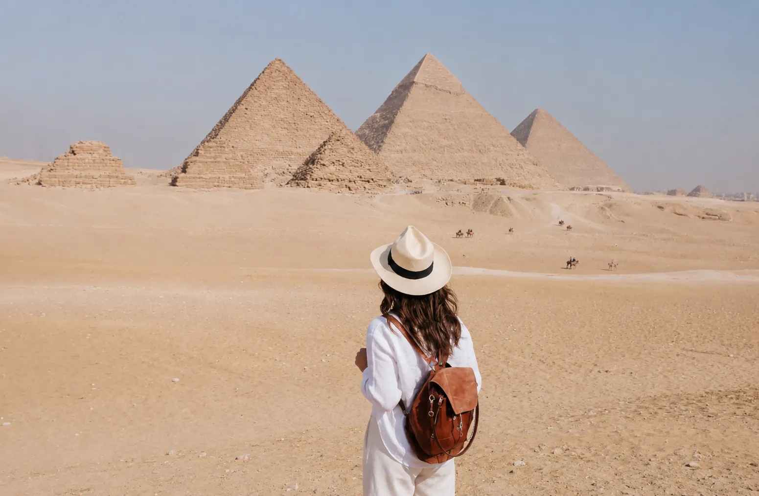 Traveler with a backpack facing the panorama of the Giza pyramids