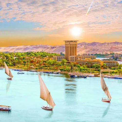 traditional wooden felucca sailboats gliding past granite rocks and sand dunes on the nile river in aswan