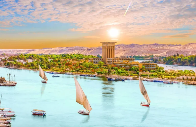 traditional wooden felucca sailboats gliding past granite rocks and sand dunes on the nile river in aswan