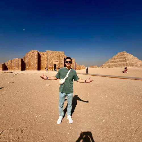 Man with open arms before the Djoser funerary complex and Step Pyramid at Saqqara
