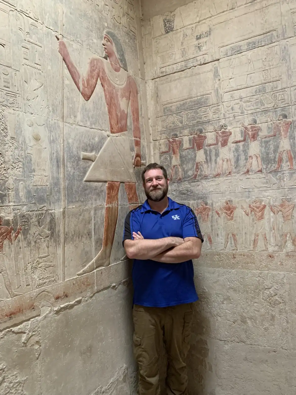 Man beside a painted relief of an ancient Egyptian figure inside a Saqqara noble's tomb