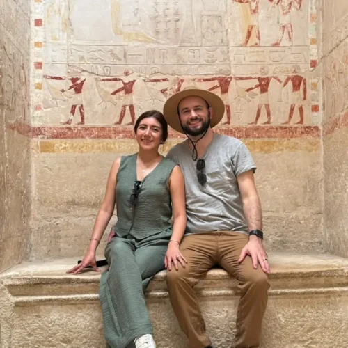 Couple seated below colourful painted reliefs inside a Saqqara noble's tomb