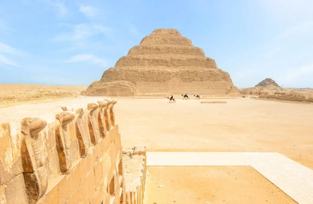 The Step Pyramid of Djoser seen past the ancient cobra frieze wall at Saqqara