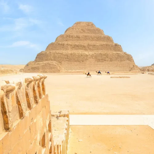 The Step Pyramid of Djoser seen past the ancient cobra frieze wall at Saqqara