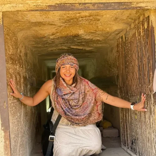 Traveler kneeling inside the narrow entrance passage of a Giza pyramid