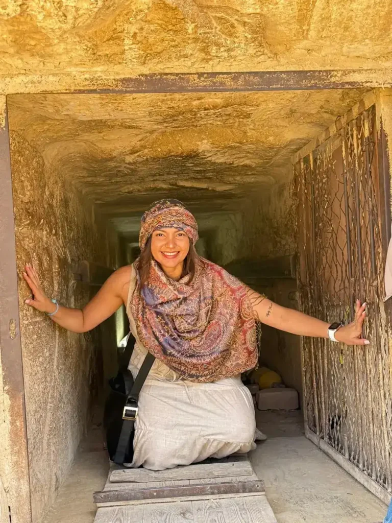 Traveler kneeling inside the narrow entrance passage of a Giza pyramid