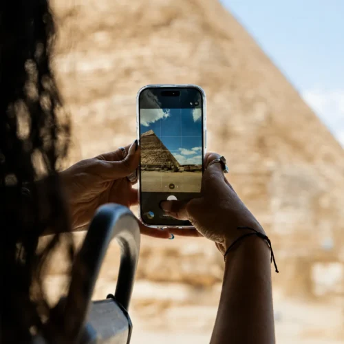 Traveler photographing the Great Pyramid of Giza with a smartphone