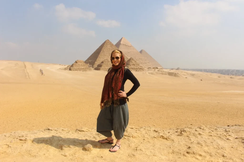Traveler in a red scarf on the Giza plateau with three pyramids behind