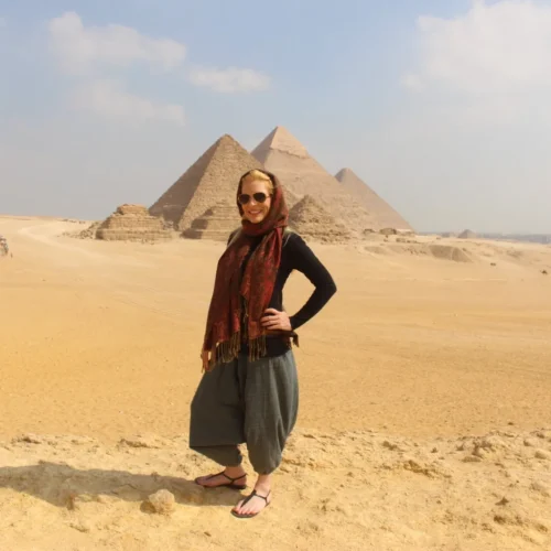 Traveler in a red scarf on the Giza plateau with three pyramids behind