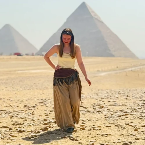 Traveler walking across the Giza plateau with the pyramids behind