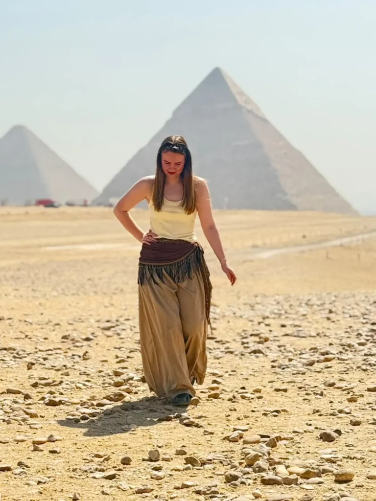 Traveler walking across the Giza plateau with the pyramids behind