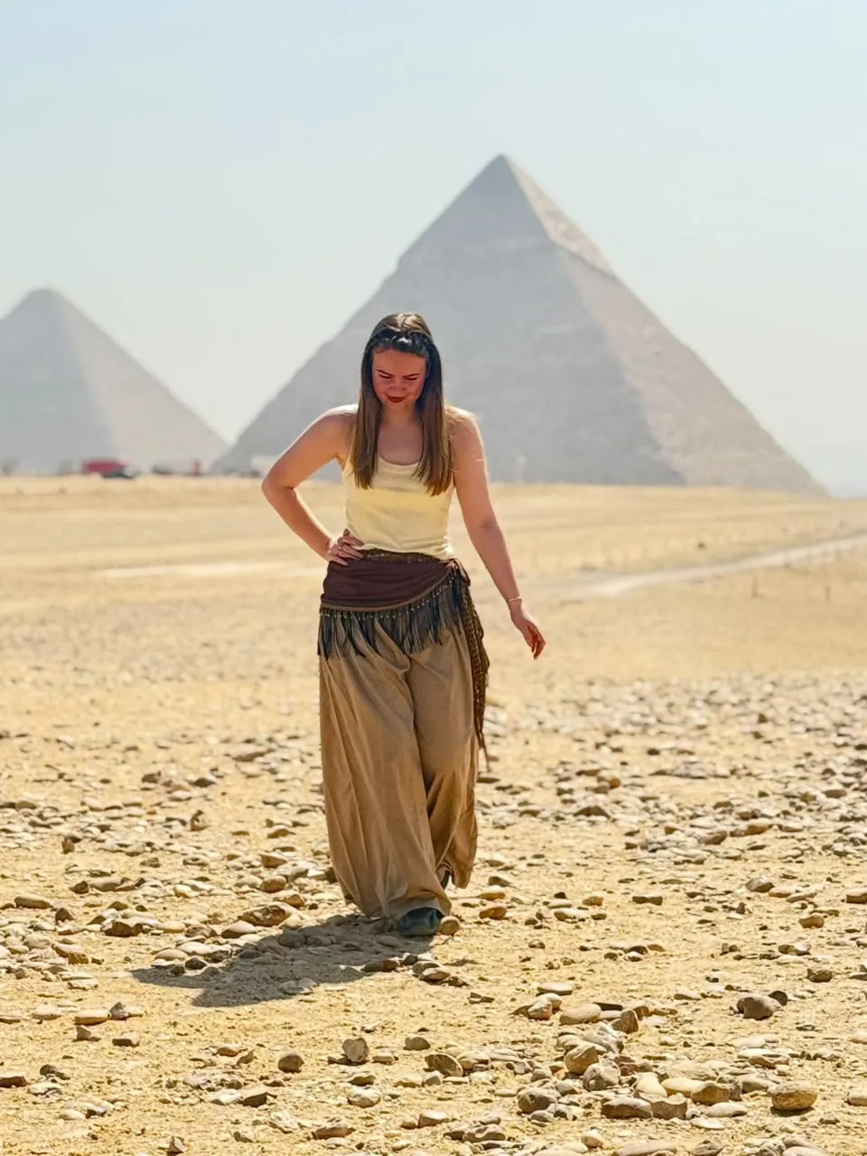 Traveler walking across the Giza plateau with the pyramids behind