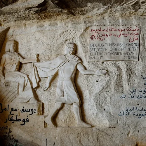 Rock-carved relief of Joseph fleeing Potiphar’s wife with bilingual Genesis inscription inside St. Simon Cave Church