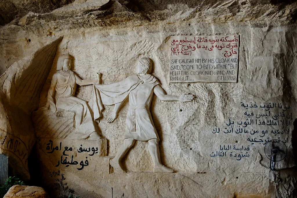 Rock-carved relief of Joseph fleeing Potiphar’s wife with bilingual Genesis inscription inside St. Simon Cave Church