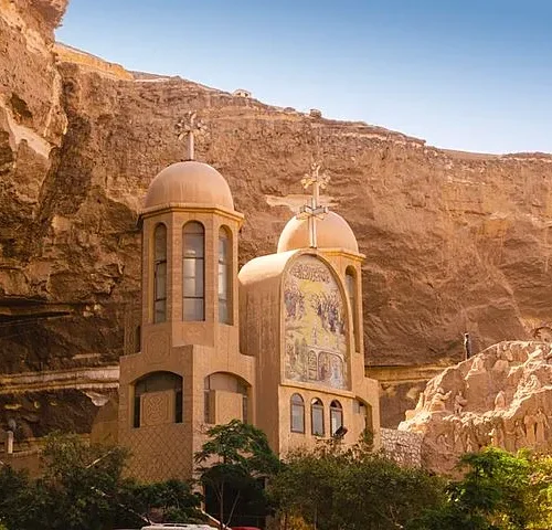 Close view of St. Simon monastery domes and religious mosaic against the Mokattam cliff under blue sky