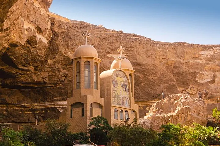 Close view of St. Simon monastery domes and religious mosaic against the Mokattam cliff under blue sky