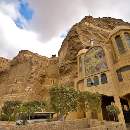 Monastery of St. Simon the Tanner built into the Mokattam cliff in Cairo, with Coptic domes, a facade mosaic, and rock carvings