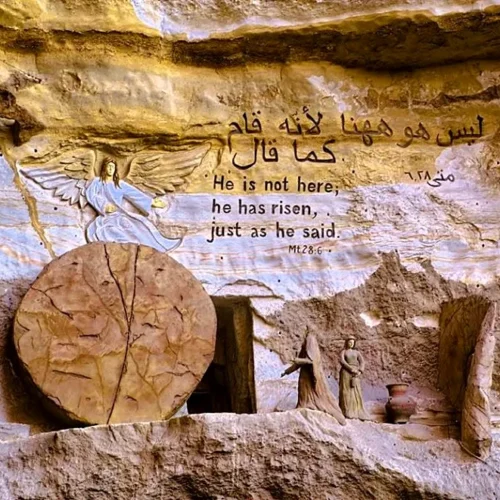 Cliff-carved Resurrection scene at St. Simon monastery with empty tomb, rolled stone, angel relief, and Matthew 28:6 text