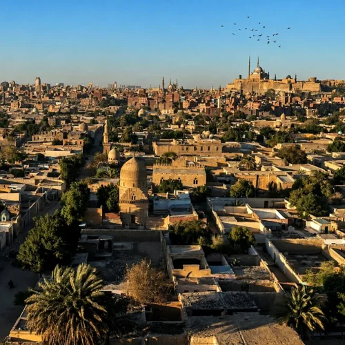 High view across Islamic Cairo toward the Citadel and Mosque of Muhammad Ali with historic domes in the foreground
