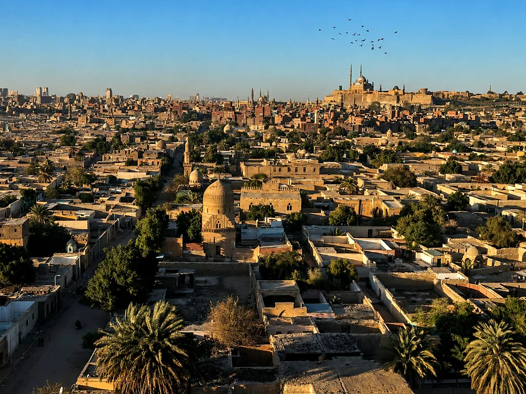 High view across Islamic Cairo toward the Citadel and Mosque of Muhammad Ali with historic domes in the foreground