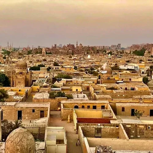 Golden-hour skyline of Cairo’s historic necropolis with ornate Islamic domes and pigeons in flight
