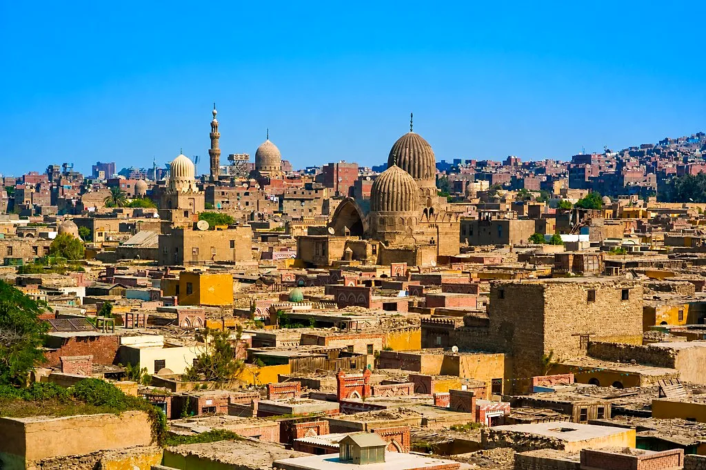 Panoramic view of Cairo’s Northern Cemetery with twin ribbed Mamluk domes and minarets under a clear blue sky